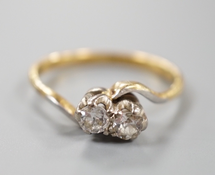 A yellow metal and plat, two stone diamond set crossover ring, size M, gross weight 2.8 grams.